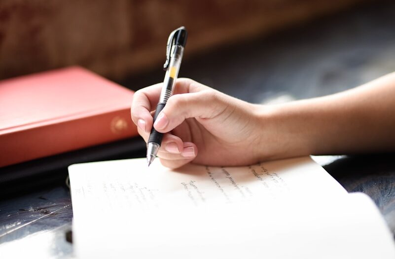 a person writing on a piece of paper with a pen