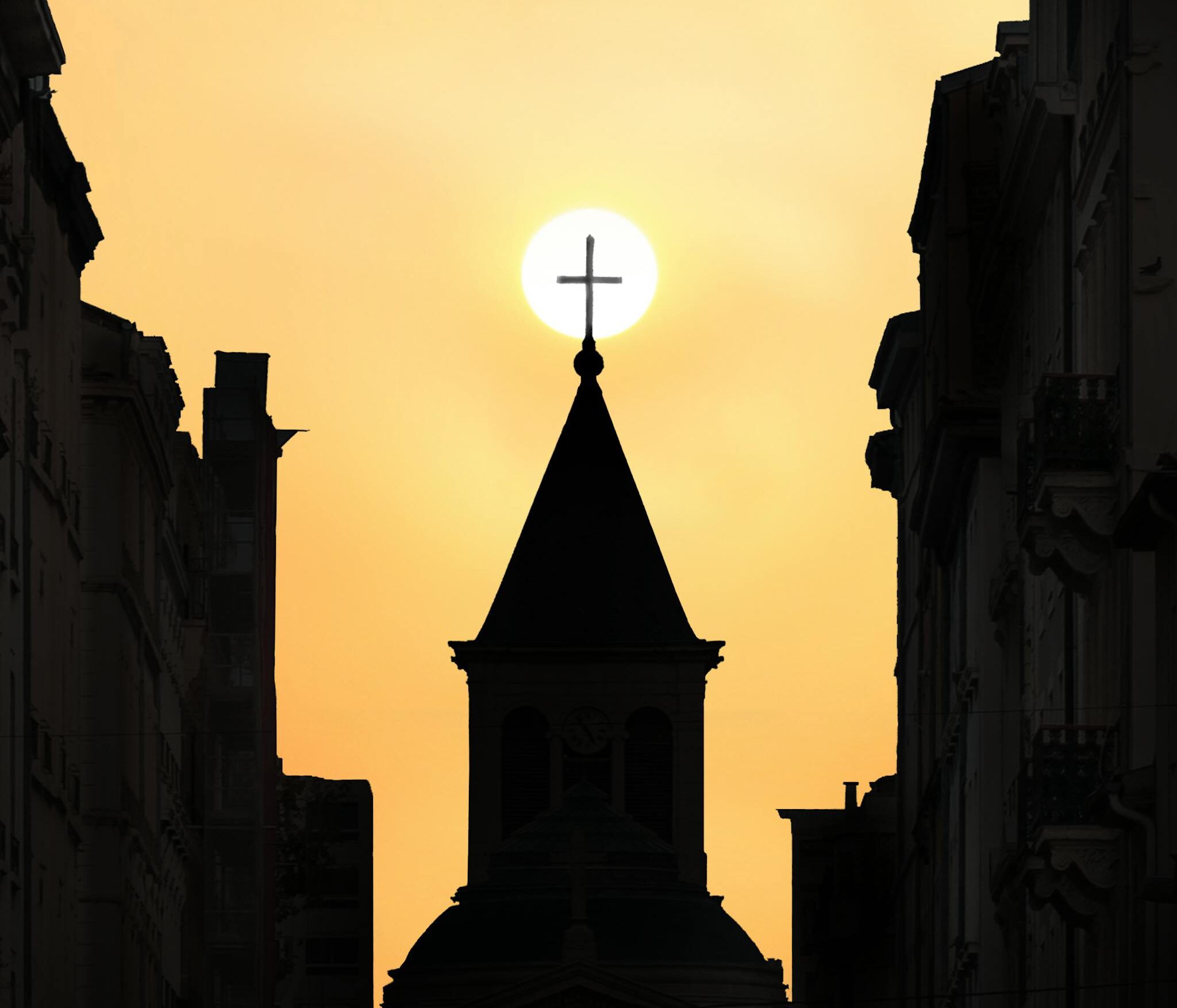 A striking silhouette of a church against a vibrant sunset in Lyon, France.