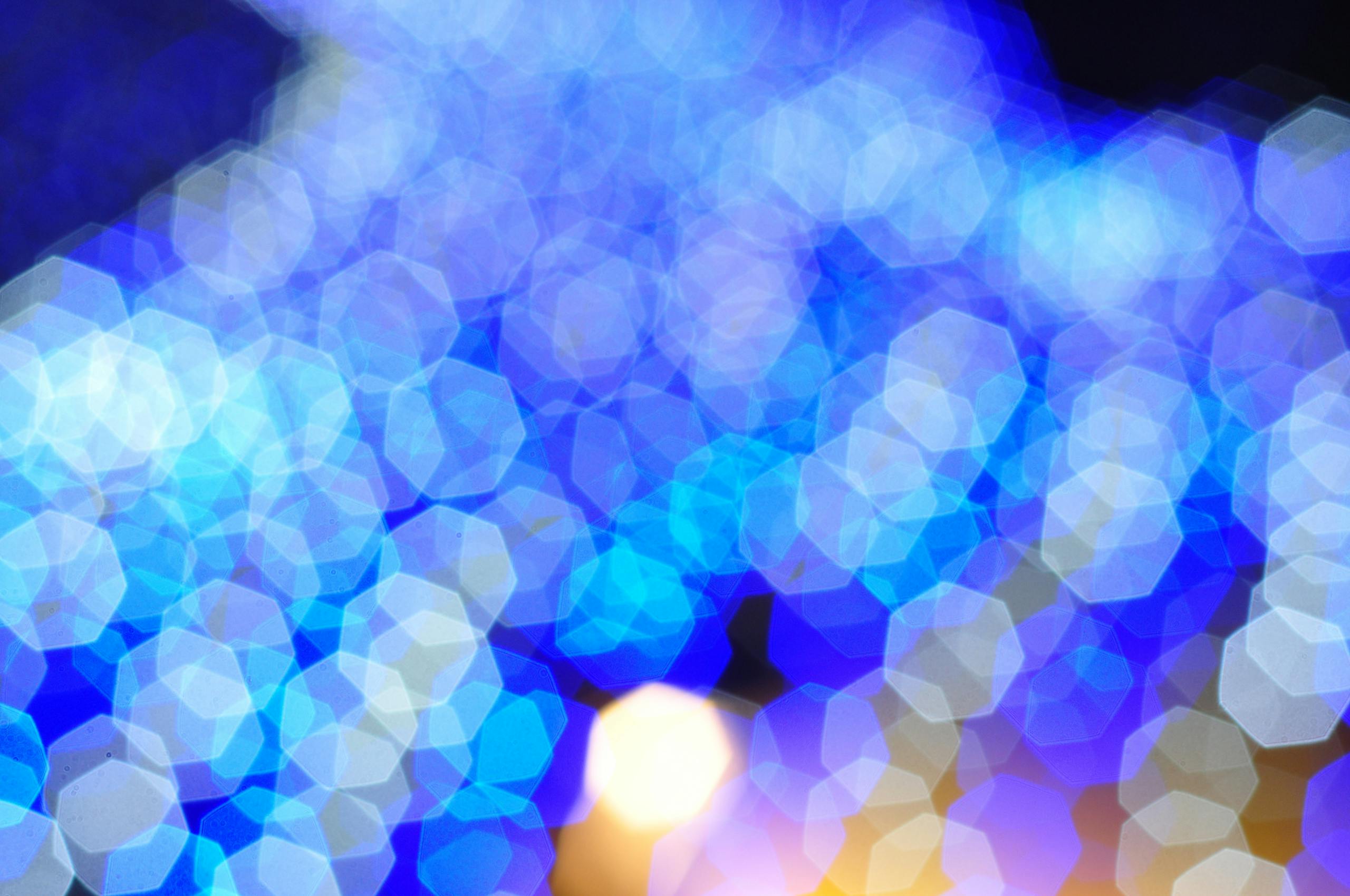 Colorful abstract bokeh background featuring vibrant blue light patterns and hexagonal shapes.